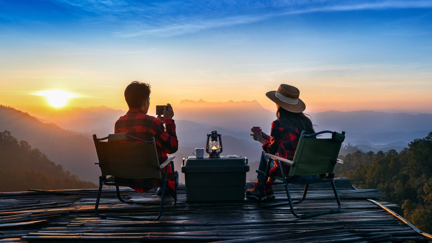 Paar auf Stühlen mit Bergblick im Sonnenuntergang