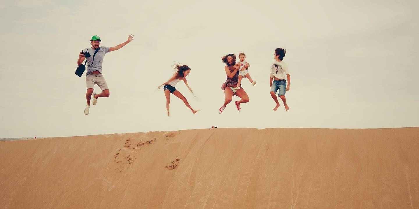 Springende familie op de duin Een familie springt in de lucht op een zandduin
