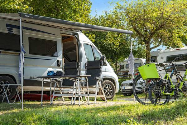 Campingmobil mit Fahrrädern unter Markise auf einem Campingplatz