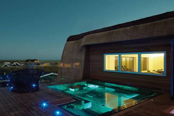 Luftaufnahme des Hvidbjerg Strand Ferieparks mit Gebäuden, Strand und Menschen.