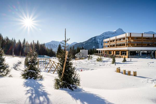 Abendansicht des Zugspitz Resorts mit beleuchtetem Gebäude und Außensitzbereich.