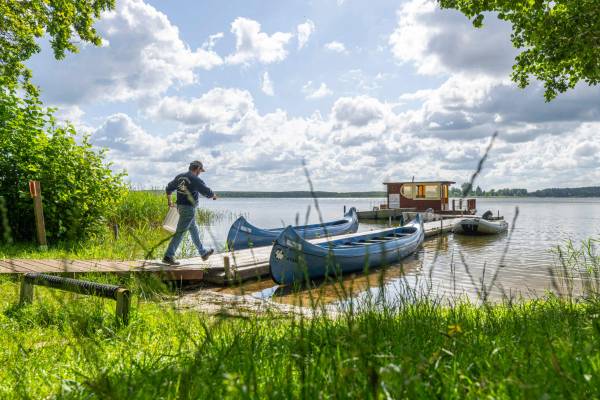 Campingplatz mit mehreren weißen Wohnwagen am See unter blauem Himmel.