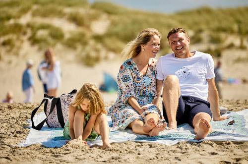 Luftfoto af Henne Strand Resort med strand, klitter og kystby.