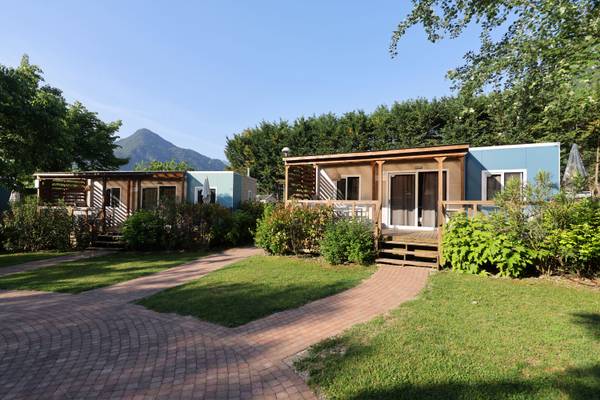 Vista aérea del camping glamping Lago Idro con montañas, lago y edificios.