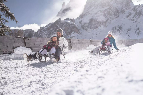 Family sled ride in the snow Caravan Park Sexten with a camper in front