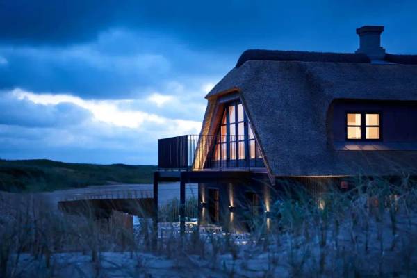 Strandhaus bei Nacht Luftaufnahme des Hvidbjerg Strand Ferieparks mit Gebäuden, Strand und Menschen.
