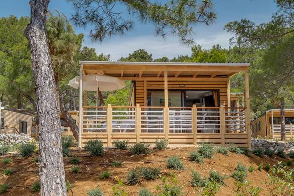 Ferien-Chalet auf Campingplatz Ein modernes Holzchalet auf einem Campingplatz mit einem offenen Balkon und einer Terrasse.