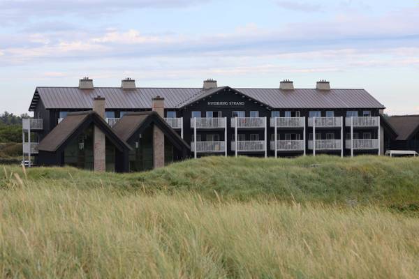Vue aérienne du camping Hvidbjerg Strand Feriepark avec des bâtiments, une plage et des personnes.