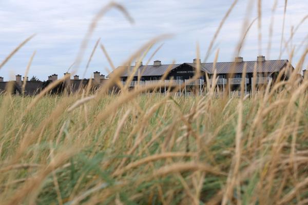 Luftfoto af Hvidbjerg Strand Feriepark camping med bygninger, strand og mennesker.