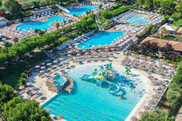 A pool at Piani di Clodia campsite with a waterfall and people swimming