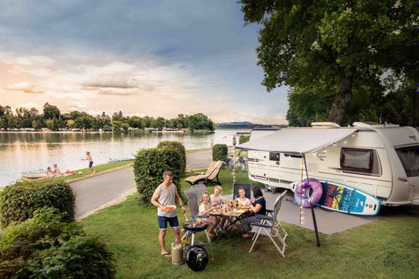 Campeggio sul lago con camper e case mobili, montagne sullo sfondo