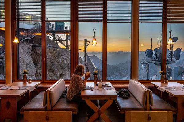 Abendansicht des Zugspitz Resorts mit beleuchtetem Gebäude und Außensitzbereich.