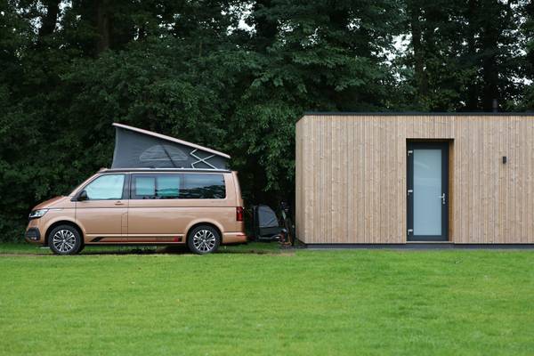 Innenbereich des Vakantiepark De Twee Bruggen Hotels mit einer hölzernen Bar, Stühlen und Tischen.