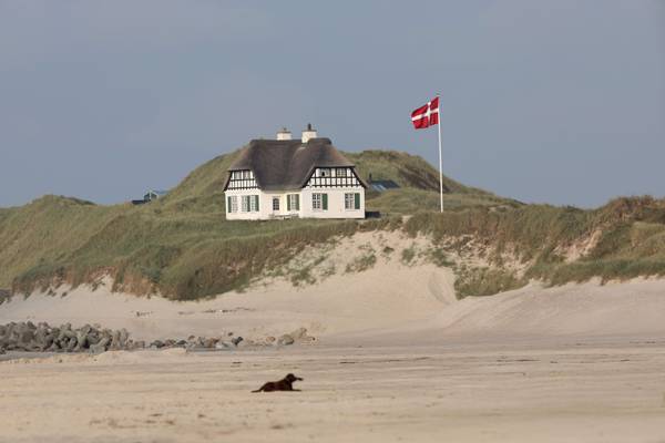 Eine Person, die am sandigen Strand von Jambo Feriepark mit Wellen im Ozean läuft