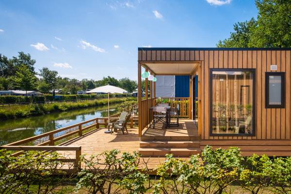 Casa vacanza in legno con terrazza e tavolo vicino all'acqua