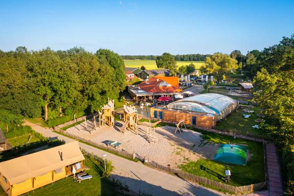 Luchtfoto van een camping met een speeltuin en omliggende gebouwen.
