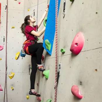 Una donna sta arrampicandosi su una parete di arrampicata.