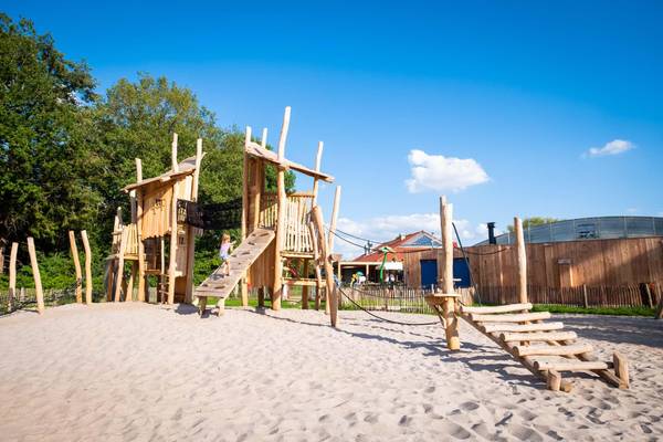 Area giochi in legno nel campeggio Papillon Country Resort con una bambina che ci arrampica.