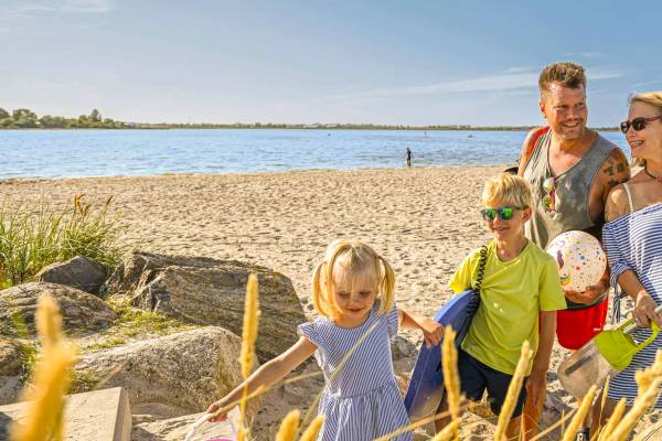 Eine Familie mit Kindern steht am Strand des Wulfener Hals.
