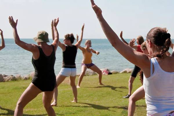 Yoga-Kurs am Wulfener Hals Campingplatz mit Menschen, die Yoga in der Nähe des Meeres praktizieren.