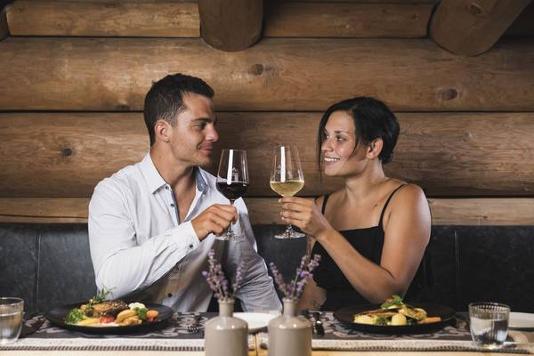 Pareja en un restaurante de madera con bebidas y comida en la mesa.