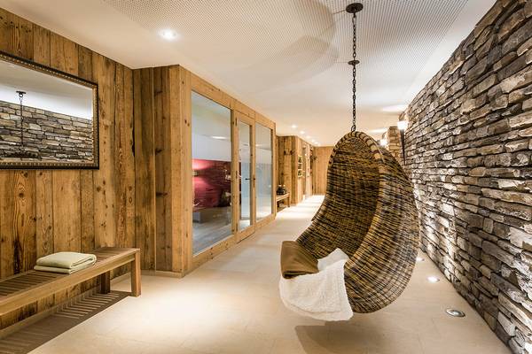 Pasillo de sauna con pared de madera y silla de mimbre con toalla