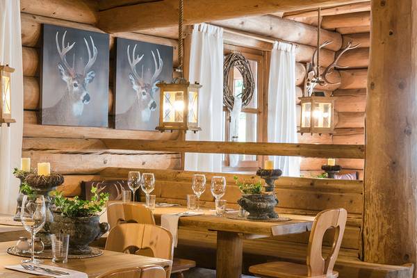 Vista interior del restaurante Alpencamping Nenzing con mesas de madera, sillas e imágenes de ciervos en la pared.