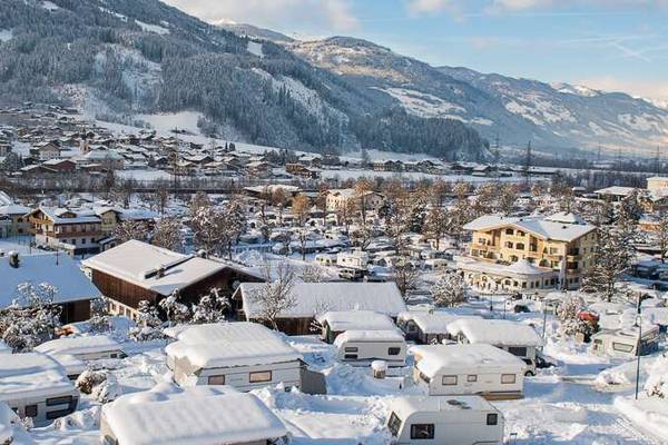 Snow-covered campsites at Erlebnis Resort Aufenfeld with mountains in the background.