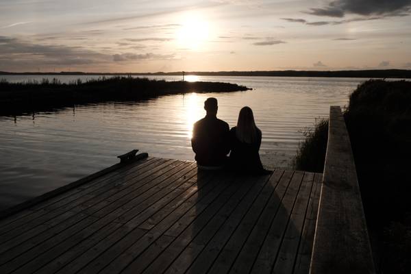 Pareja sentada en un muelle en Feddet Strand Resort al atardecer