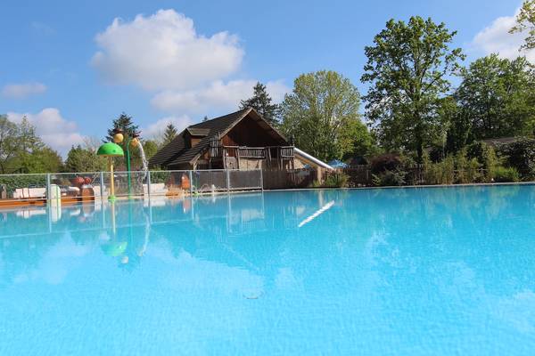 Zwembad bij Camping De Wildhoeve met een houten lodge en bomen