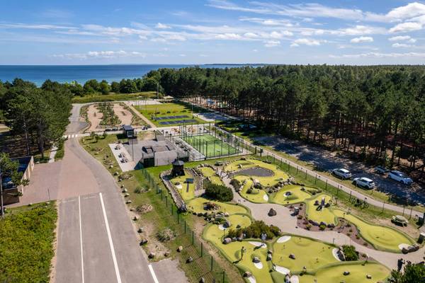 Vista aérea del Feddet Strand Resort con un campo de golf, cancha de tenis y playa al fondo.