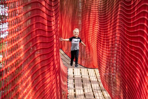 Un niño pequeño en el camping Feddet Strand Resort en un puente de aventura rojo