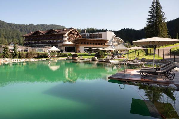 Außenbereich des Zugspitz Resort Campingplatzes mit großem Pool und Liegestühlen unter Schirmen.