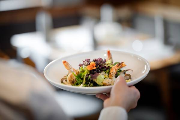 Eine Hand, die eine weiße Schüssel mit Garnelensalat im Zugspitz Resort Camping hält.