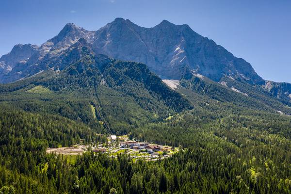Luftaufnahme des Zugspitz Resort Campingplatzes umgeben von Bergen und Bäumen.