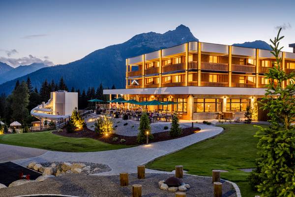 Abendansicht des Zugspitz Resorts mit beleuchtetem Gebäude und Außensitzbereich.