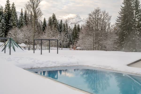 Wintercampingplatz mit Pool im Zugspitz Resort, umgeben von Schnee und Bäumen.