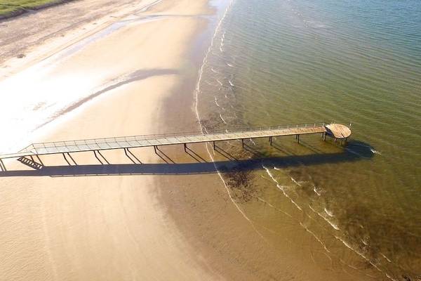 Luftaufnahme des Hvidbjerg Strand Ferieparks mit einer Holzbrücke über dem Wasser.