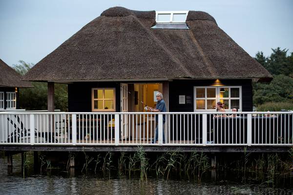 Ein Ferienhaus im Hvidbjerg Strand Feriepark mit einem Mann, der auf der Veranda angelt.