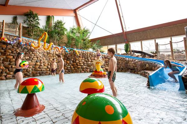 Kinder spielen im Innenpool mit Rutsche im Hvidbjerg Strand Feriepark.