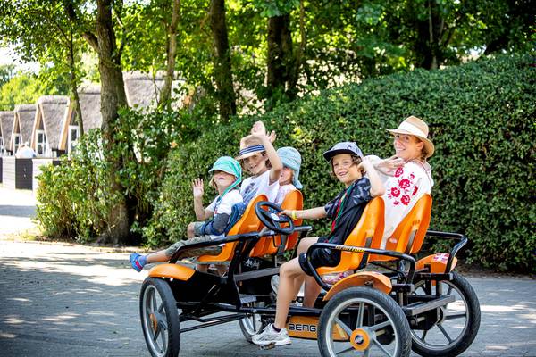 Familie fährt auf einem orangefarbenen Fahrzeug im Campingplatz Hvidbjerg Strand Feriepark.