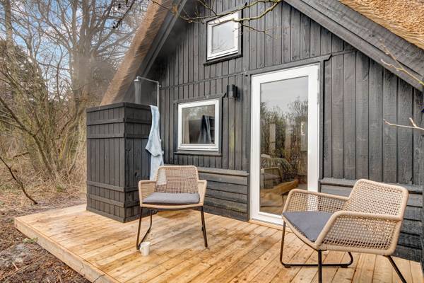 Ferienhaus auf Hvidbjerg Strand Feriepark mit Holzterrasse und Korbstühlen.