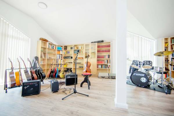 Ein Raum mit Musikinstrumenten und einem Bücherregal, mit Gitarren, Trommeln und Violinen.