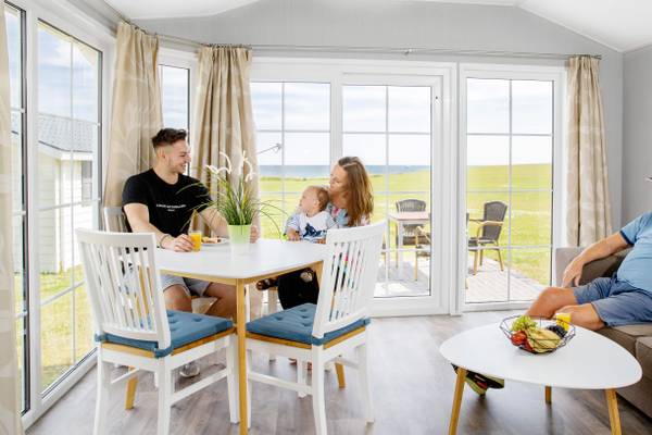 Familie sitzt an einem Tisch im Campingplatz mit Blick auf das Meer.