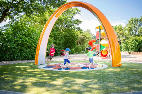 Kinder spielen im Freizeitpark unter einem Bogen.