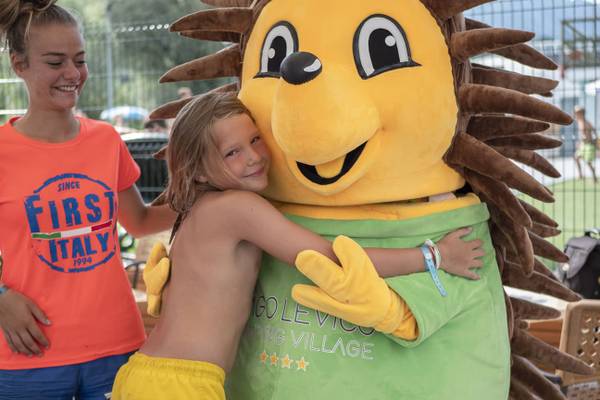 En lille pige krammer en stor maskot på Lago Levico Camping Village.