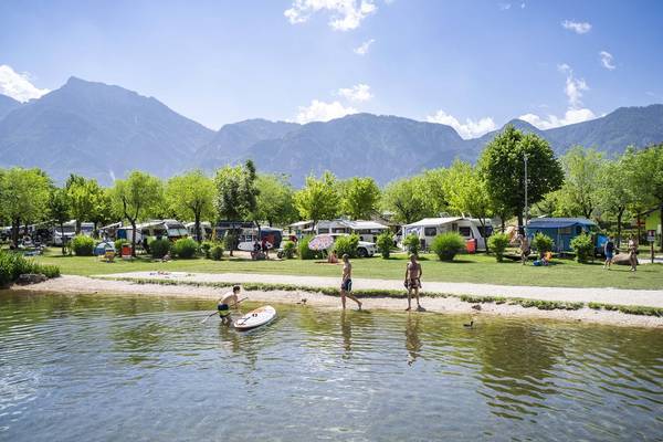 Campingplads ved søen med bjerge i baggrunden