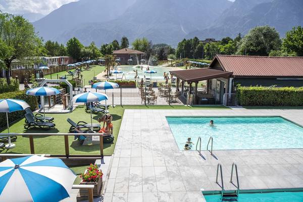 Udendørsområde på Lago Levico Camping Village med pool og liggestole.