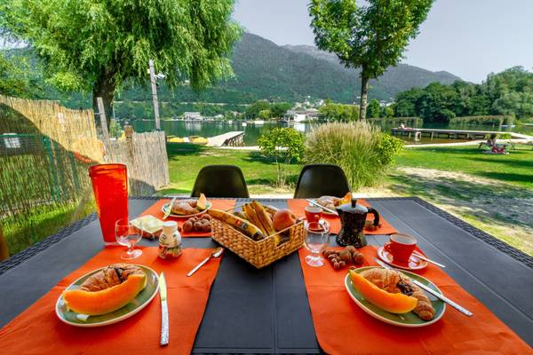 Frukost på et bord ved Lago Levico Camping Village med udsigt til søen og bjergene.