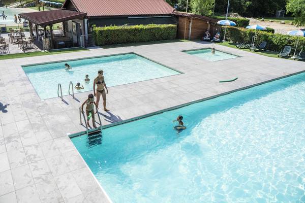 Swimmingpool på Lago Levico Camping Village med svømmende og slappe mennesker.